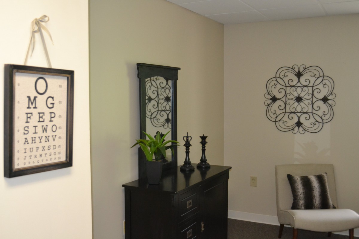A stylishly decorated corner of a room featuring a dresser with a mirror, decorative items, and wall art.