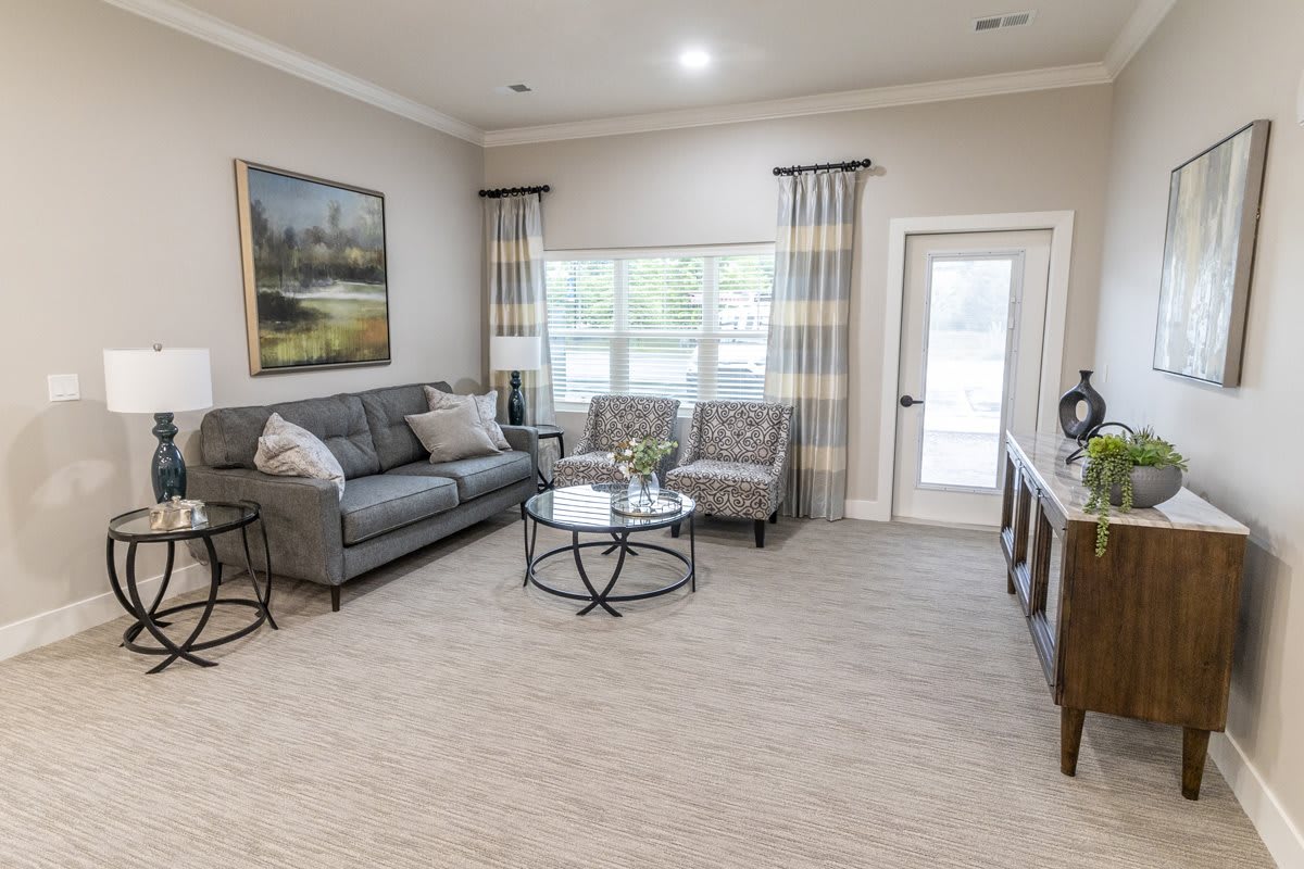 A cozy living room with a sofa, two chairs, and a coffee table set on a carpeted floor.