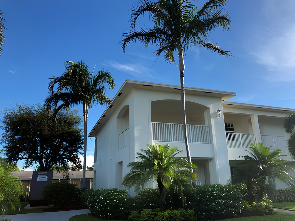 A tropical house with palm trees under a clear blue sky.