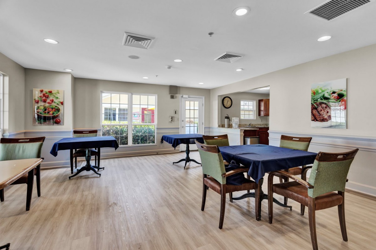 A bright and modern dining area with tables and chairs, featuring large windows.