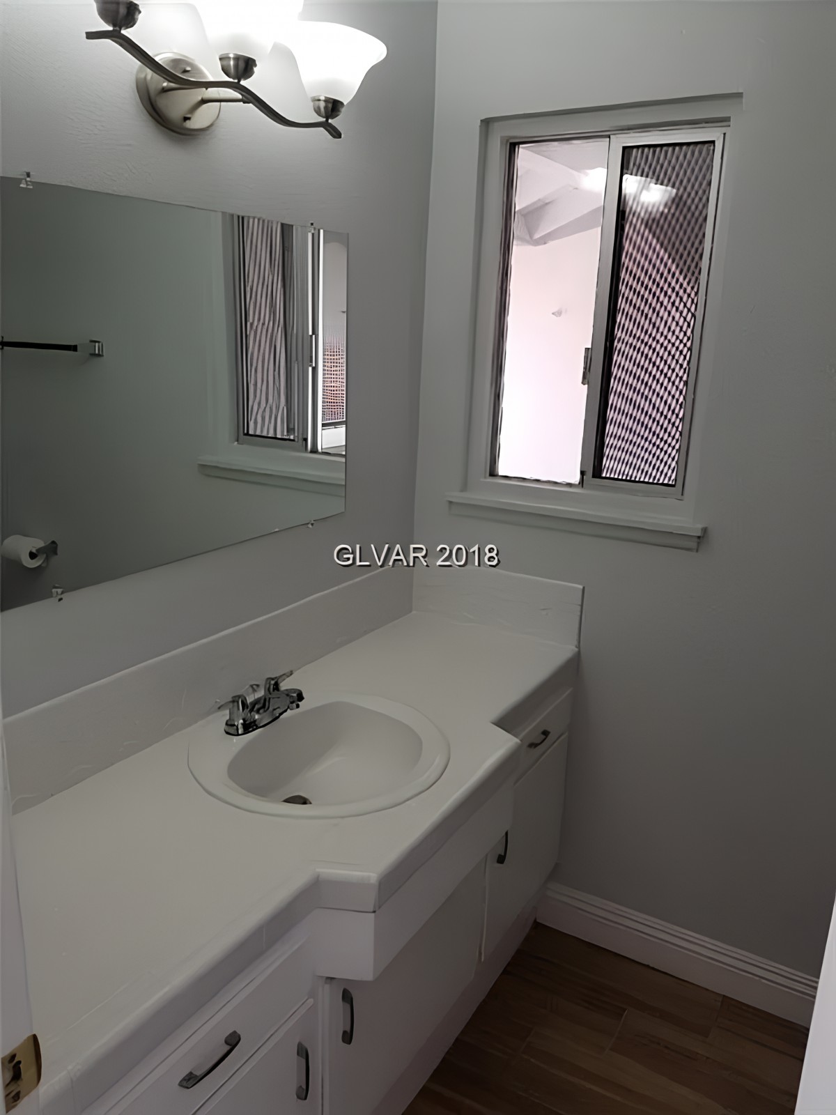 A clean bathroom featuring a sink with a large mirror and a window.