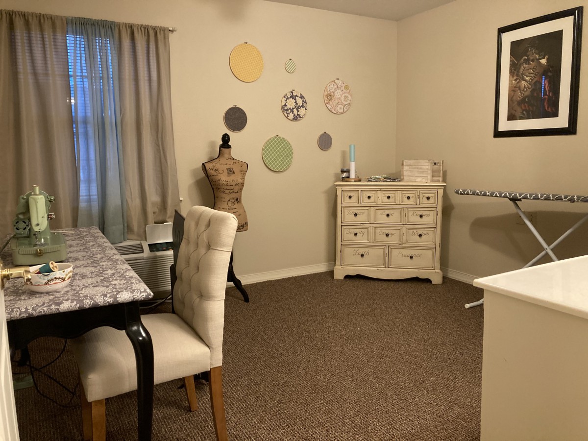 A cozy sewing room featuring a mannequin, decorative wall art, and an ironing board.
