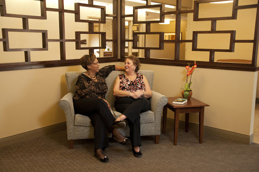 Two women enjoying a friendly conversation on a sofa in a cozy indoor setting.