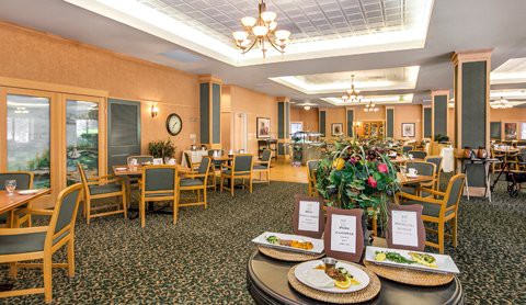 Elegant dining room setup with tables, chairs, and chandeliers, featuring a buffet table.
