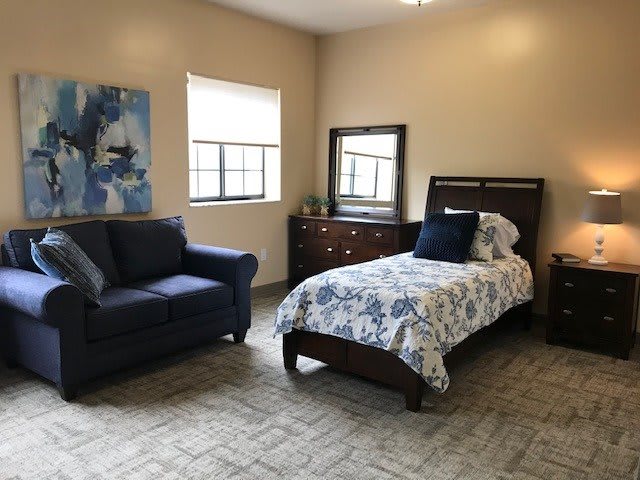 A cozy bedroom with a single bed, armchair, and dresser.