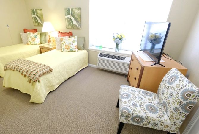 A cozy bedroom with neatly arranged furniture including a bed, chair, and television.