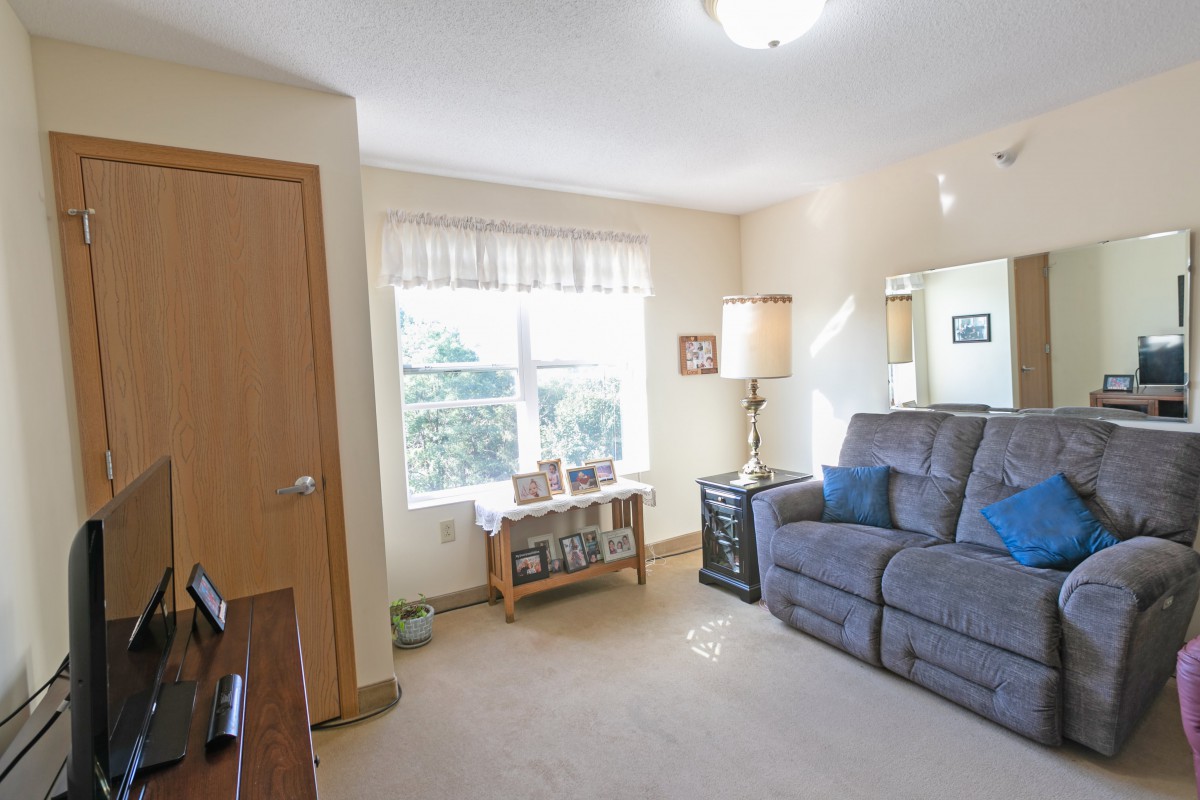 A cozy living room with a comfortable sofa, lamp, and a window letting in natural light.