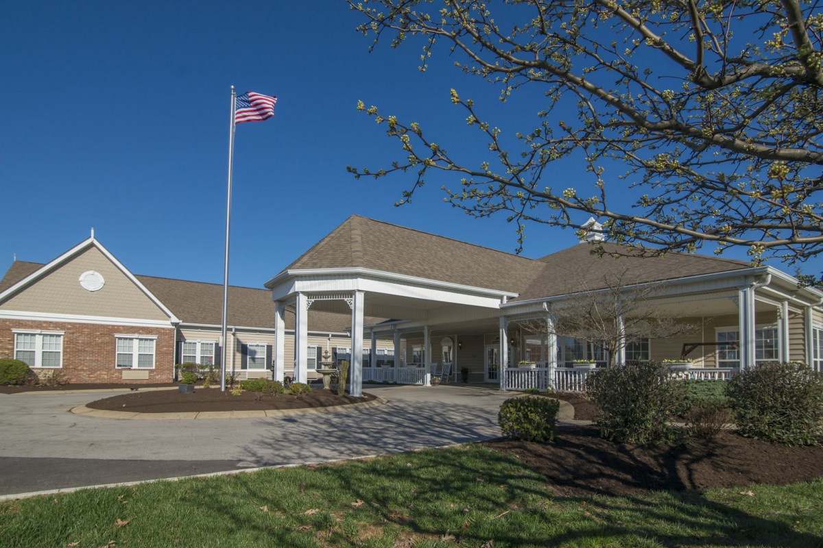 The entrance to a building with an American flag flying on a clear day.