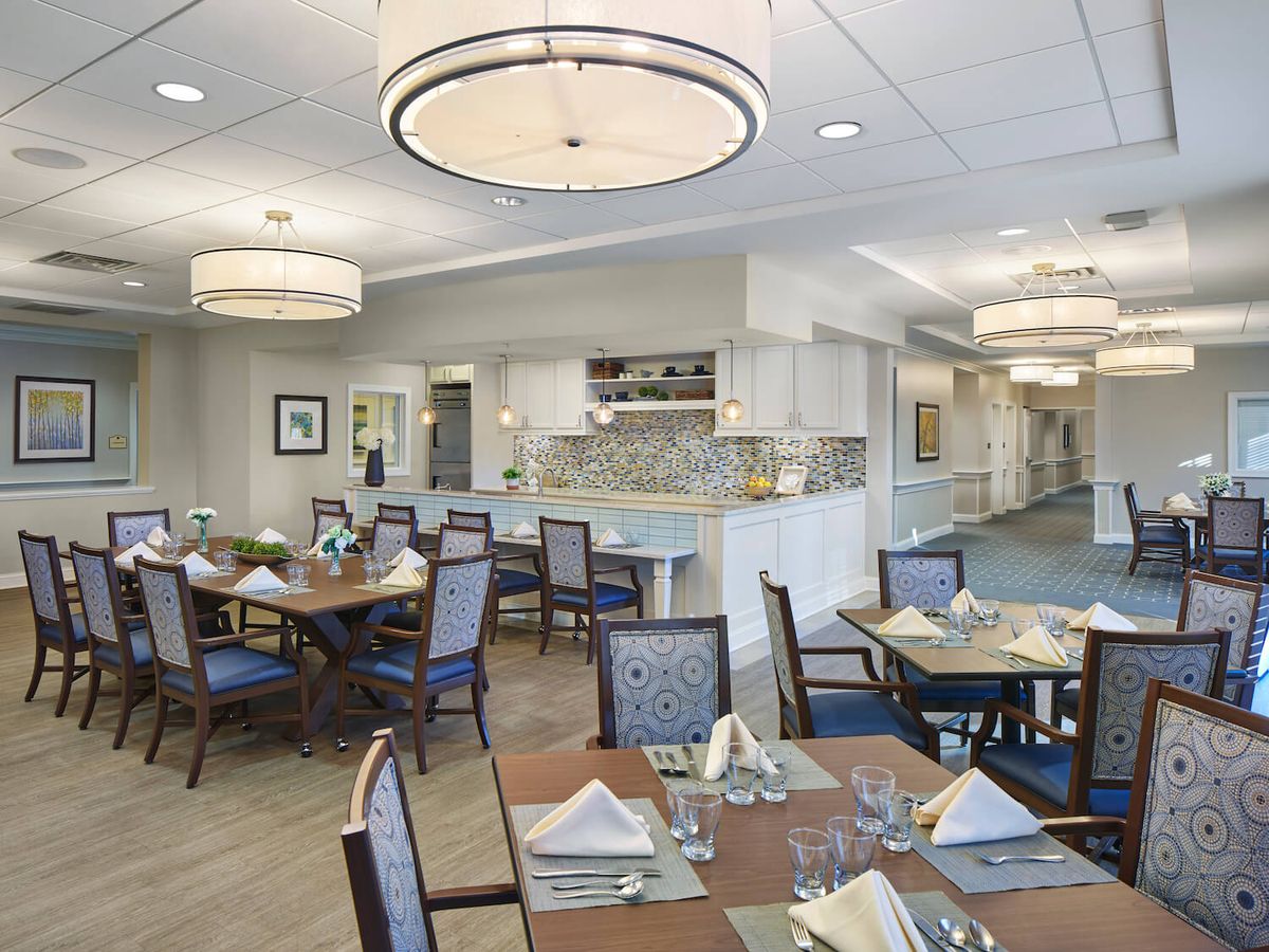 A modern dining room with neatly arranged tables, chairs, and decorative lighting.