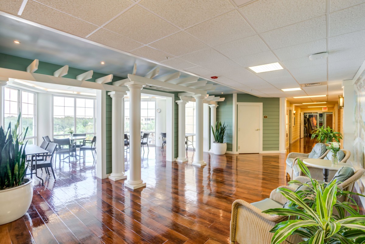 A spacious and modern lobby area with hardwood floors, decorative columns, and large windows.