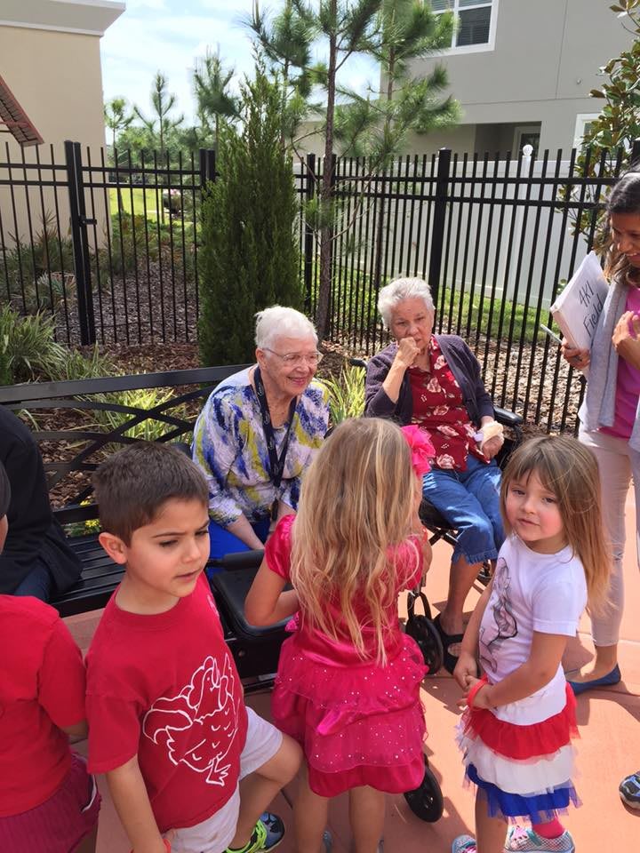 A group of children interacting with older adults outdoors, showcasing a community gathering.