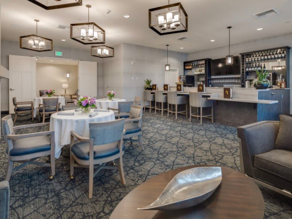 A modern dining area with round tables, comfortable chairs, and a stylish bar.