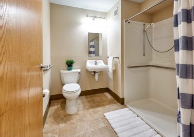 A modern bathroom featuring a toilet, sink, mirror, and shower.