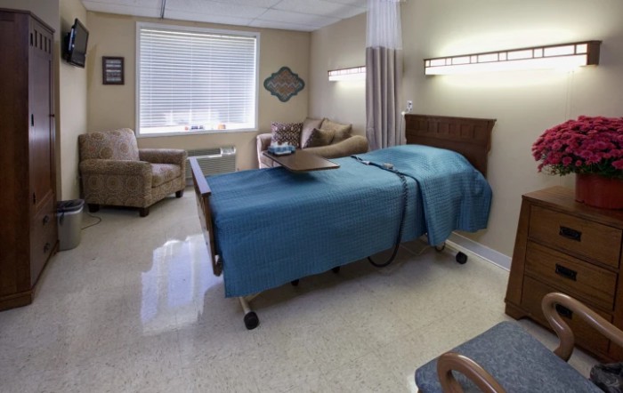 A hospital room with a bed and seating area.