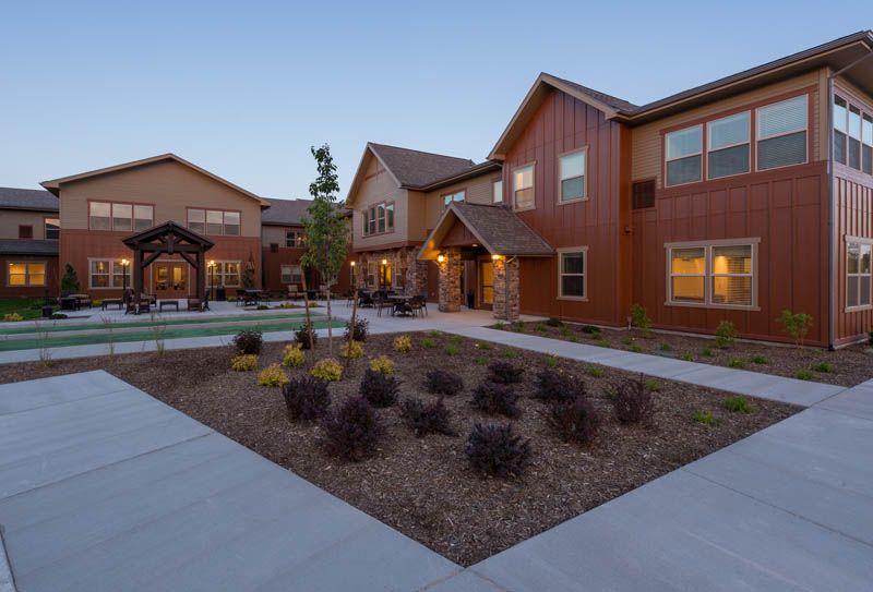 A modern residential building with a landscaped garden area during the evening.
