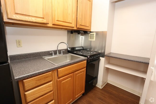 Compact kitchen with wooden cabinets, a sink, and a small stove.