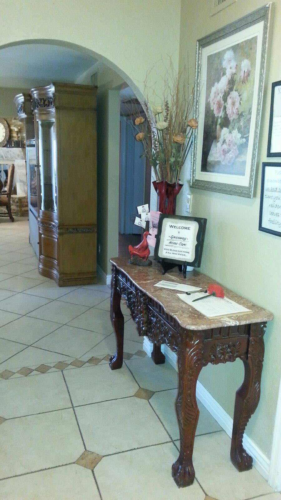 A decorative table with flowers and a framed sign in a hallway.