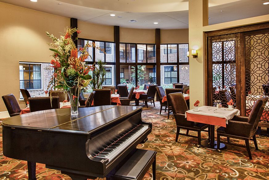 A beautifully decorated dining area featuring a grand piano and elegant floral arrangements.