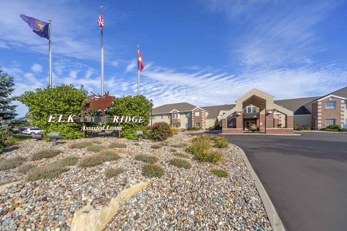 A landscaped entrance to a building with flags and a clear blue sky.