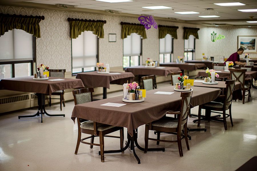 An empty dining room with decorated tables and chairs, featuring floral centerpieces.