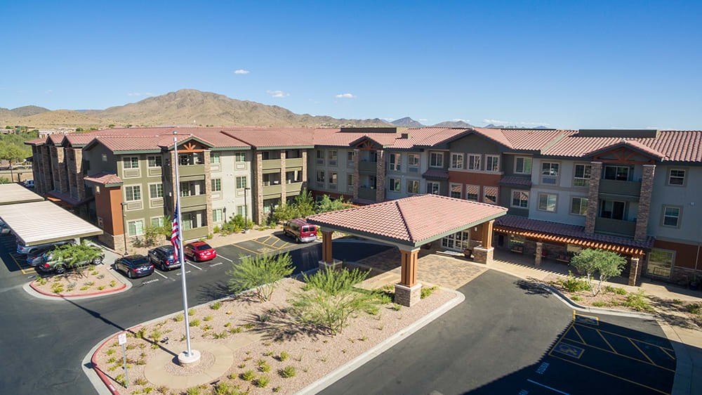 A modern residential building with a spacious parking area and mountain views.