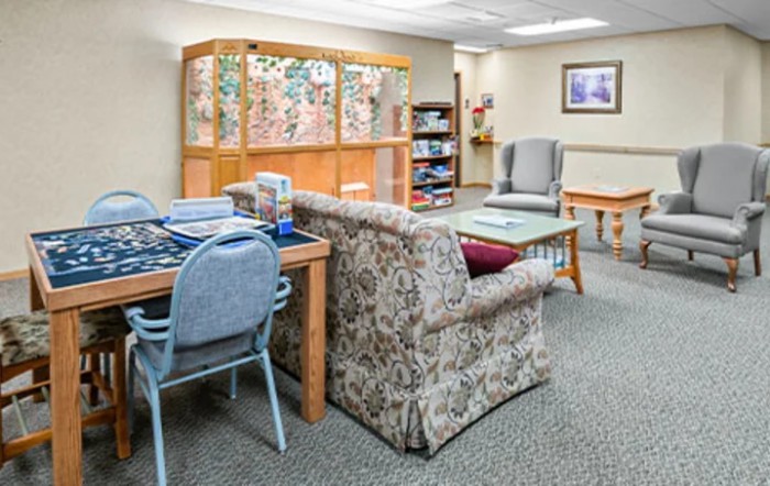 A cozy waiting room with comfortable seating, a bookshelf, and a table.