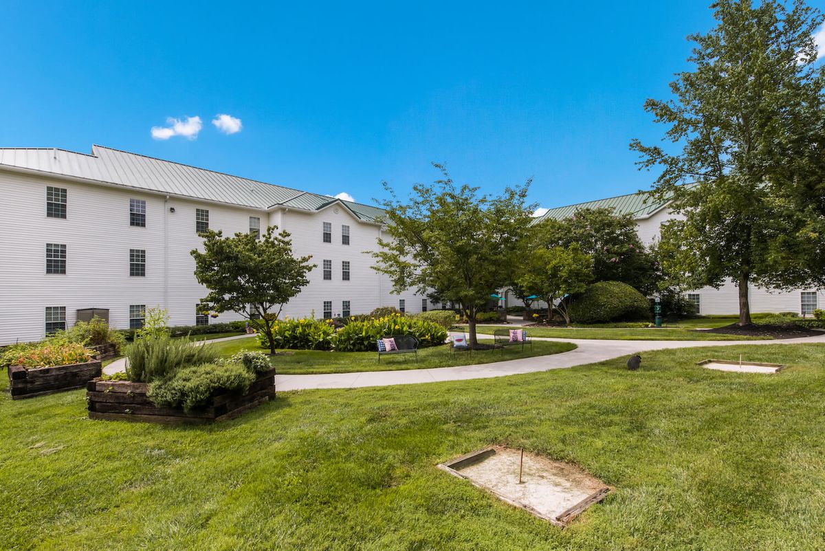 A well-maintained residential building surrounded by green landscaping and trees under a clear blue sky.