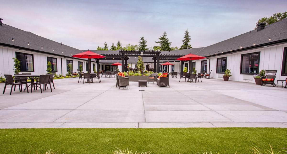 Spacious outdoor patio area with red umbrellas and comfortable seating.