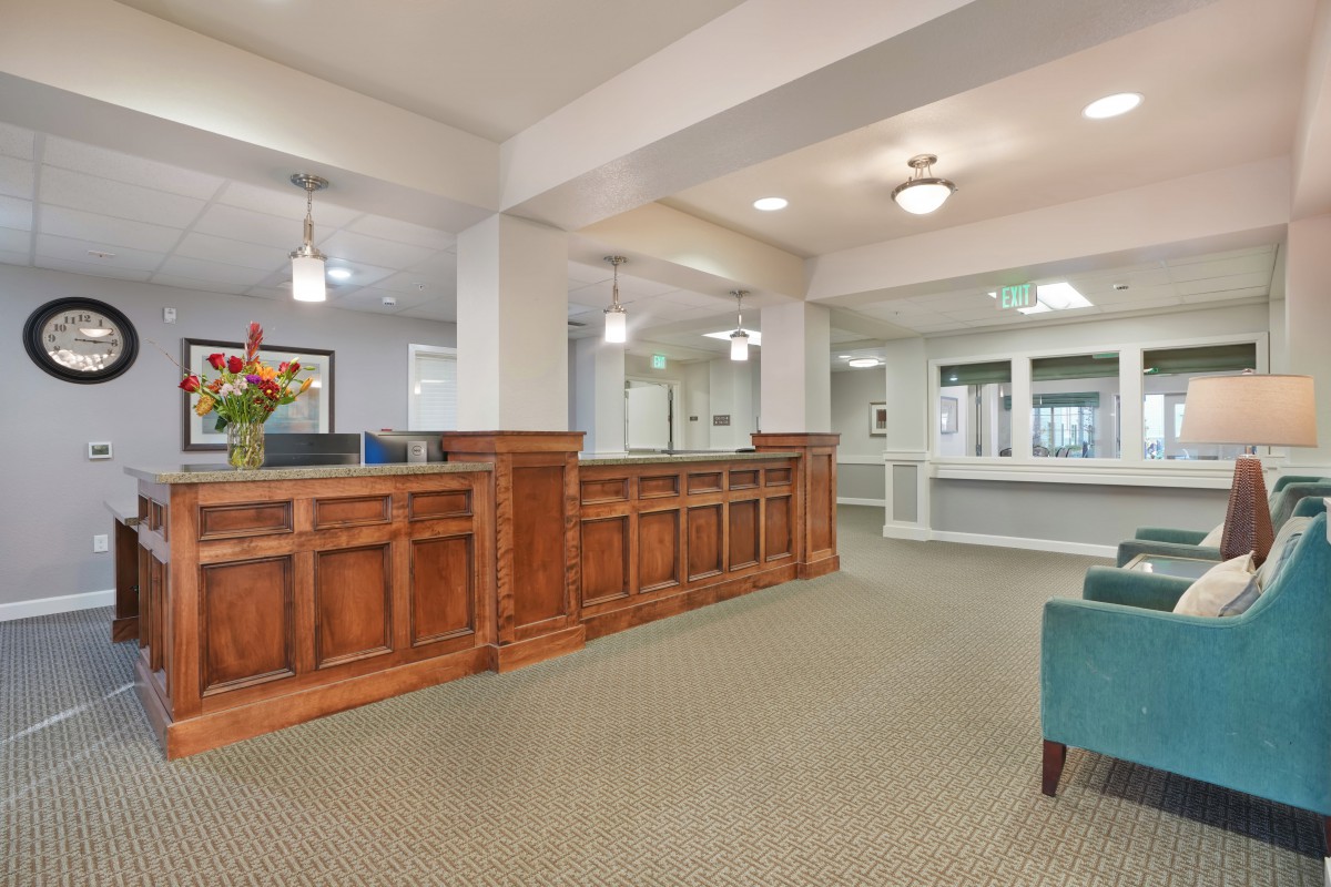 A spacious and well-lit reception area featuring wooden counters and comfortable seating.