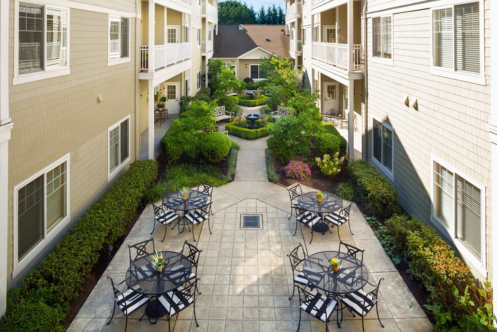 A serene courtyard with outdoor seating and lush landscaping between apartment buildings.