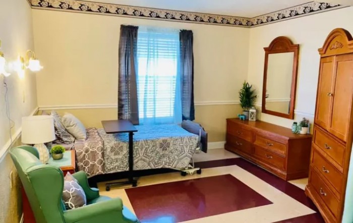 A cozy bedroom with a bed, dresser, and window with curtains.