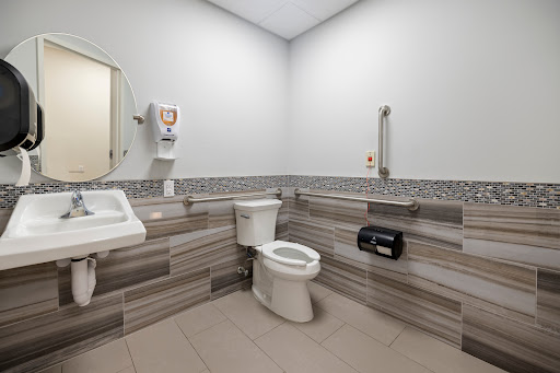A modern accessible bathroom featuring a toilet, sink, and hand dryer.
