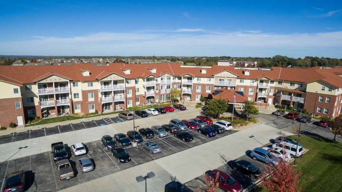Aerial view of a residential apartment complex with a parking lot in front.
