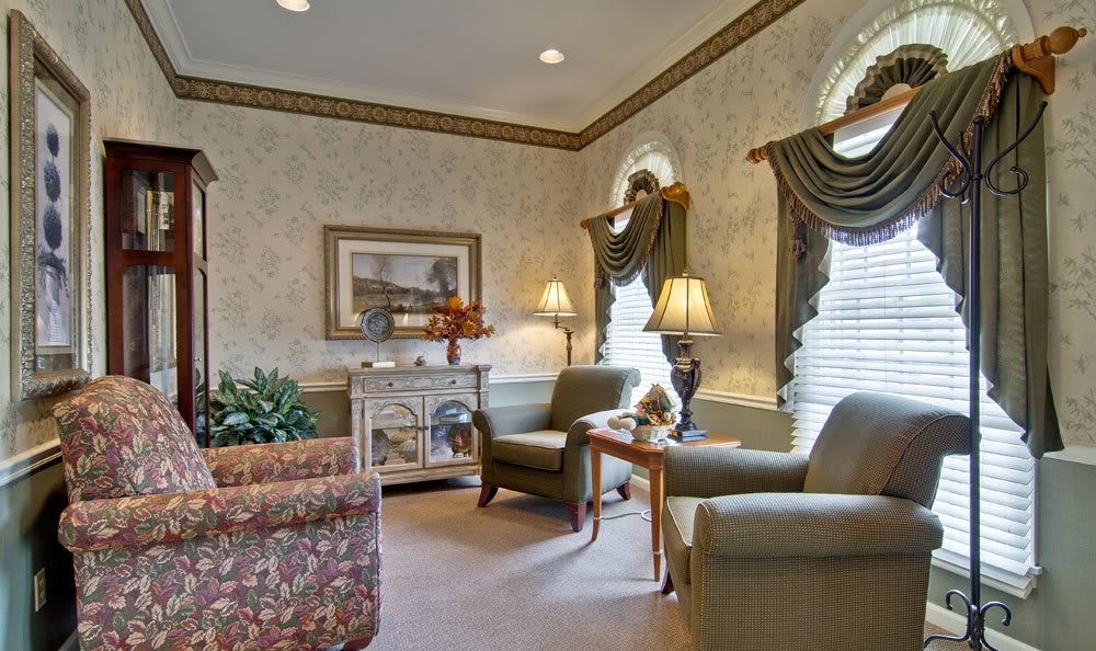 A traditionally decorated living room with armchairs, ornate curtains, and a cozy atmosphere.