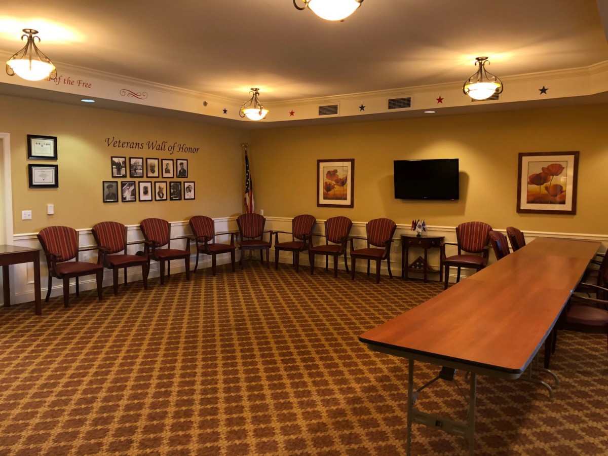 An empty conference room with arranged chairs, a mounted television, and decorative wall art.