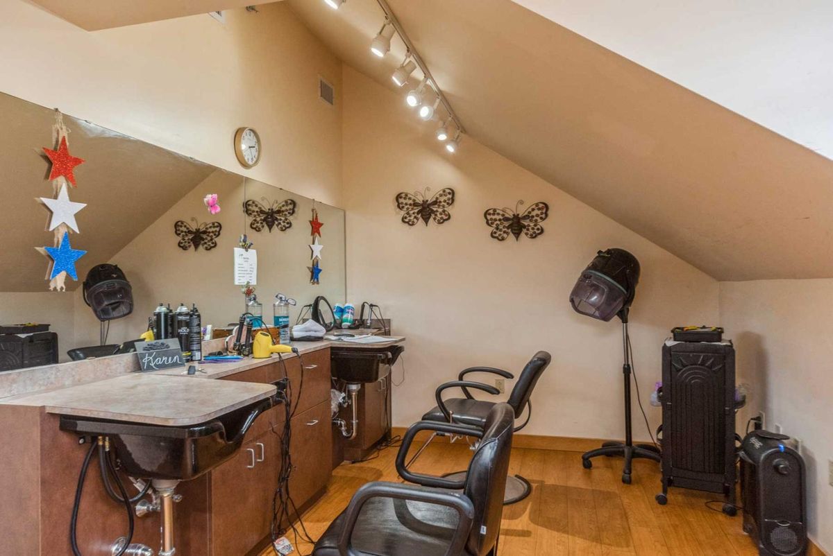 A cozy hair salon setup with chairs, mirrors, and hair styling equipment under warm lighting.