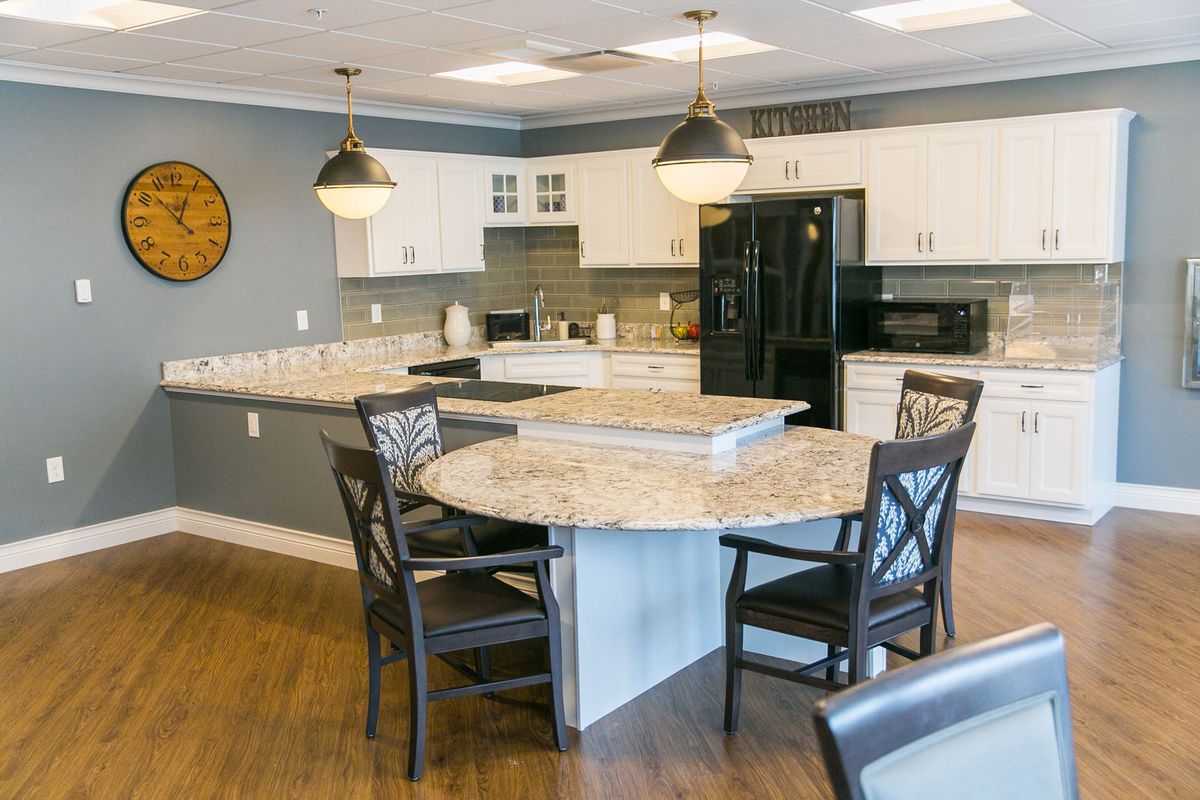 A modern kitchen featuring a central round table with chairs, stylish lighting, and sleek countertops.
