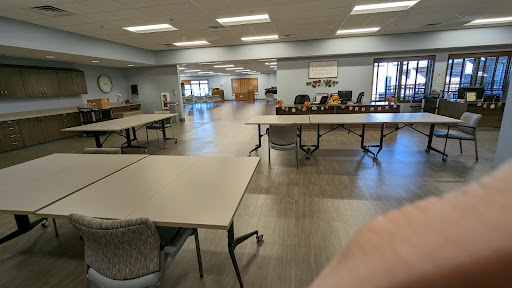 A spacious community room set up with tables and chairs, ready for an event.