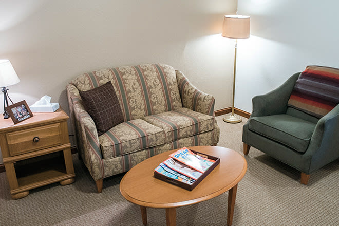 A cozy living room with a patterned sofa, green armchair, and a wooden coffee table.