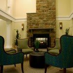 A cozy seating area with armchairs arranged around a stone fireplace.
