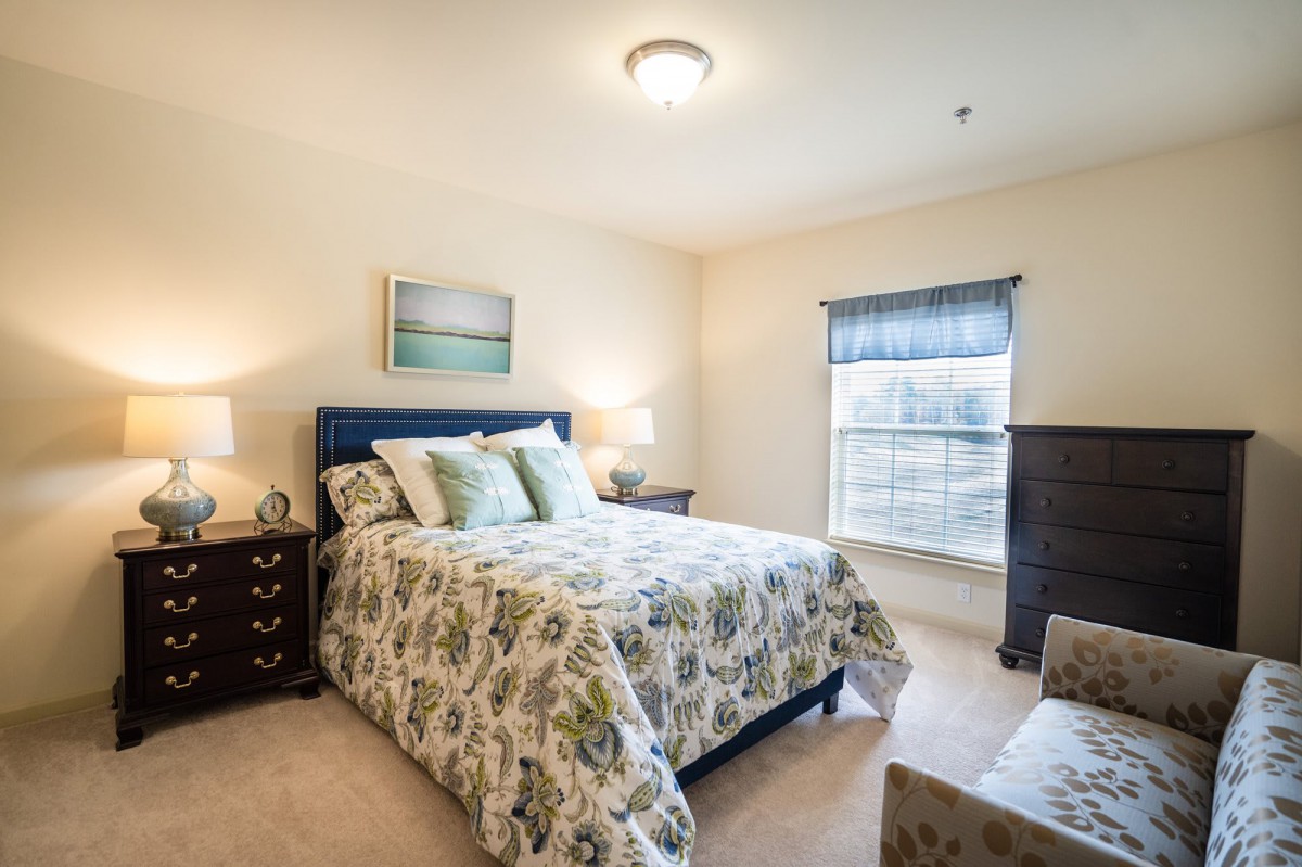 A cozy bedroom with floral bedding, soft lighting, and a window view.