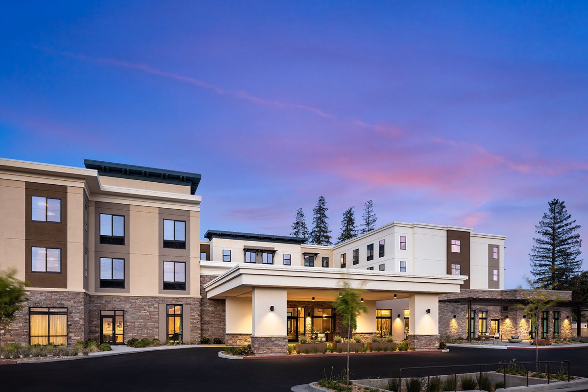 A modern hotel building exterior during the evening with a colorful sky.