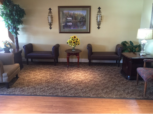 A cozy and inviting lobby area featuring comfortable seating, decorative plants, and a vibrant flower arrangement.
