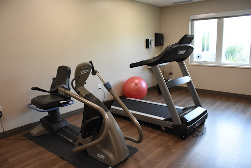 A small home gym featuring a treadmill, elliptical machine, and a fitness ball.