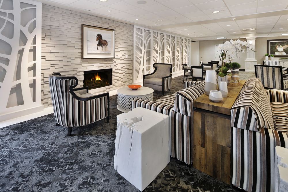 A modern living room featuring striped furniture, a cozy fireplace, and elegant artwork.