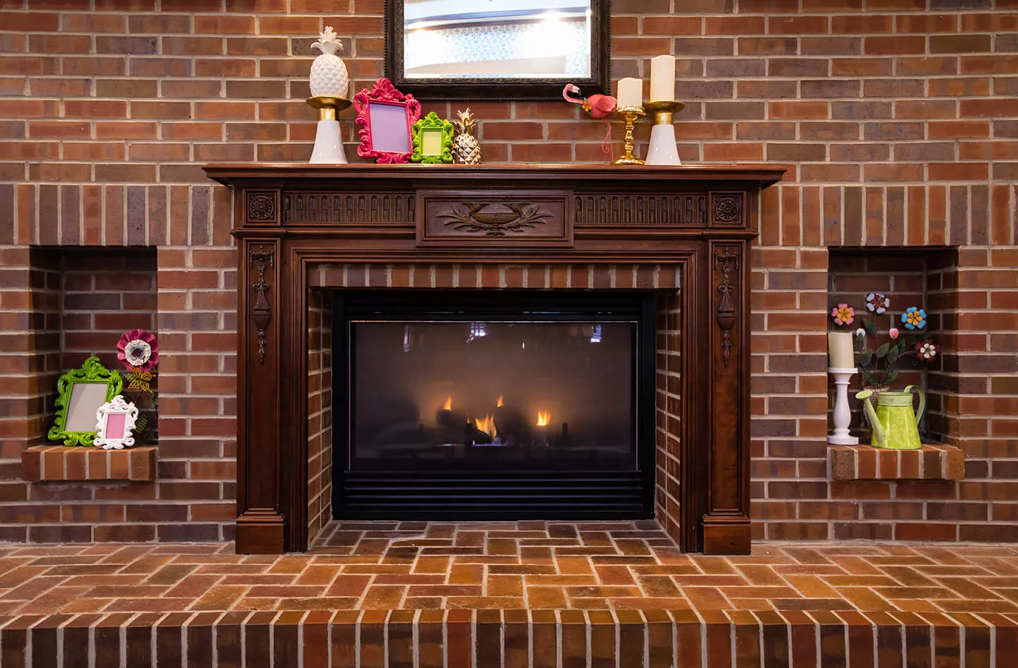 A cozy brick fireplace with a decorated mantel, featuring candles and home decor.
