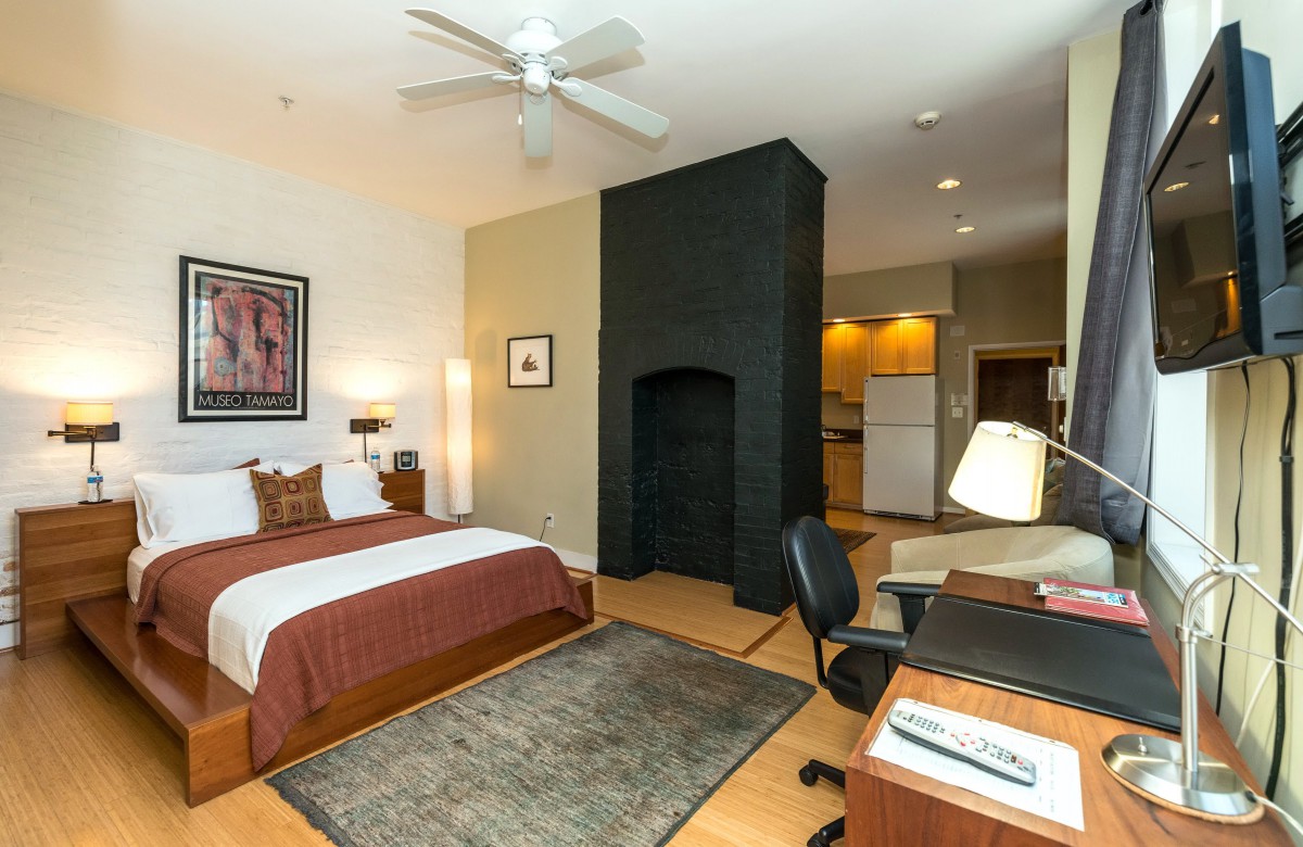 A modern bedroom with a cozy bed, home office setup, and stylish decor.