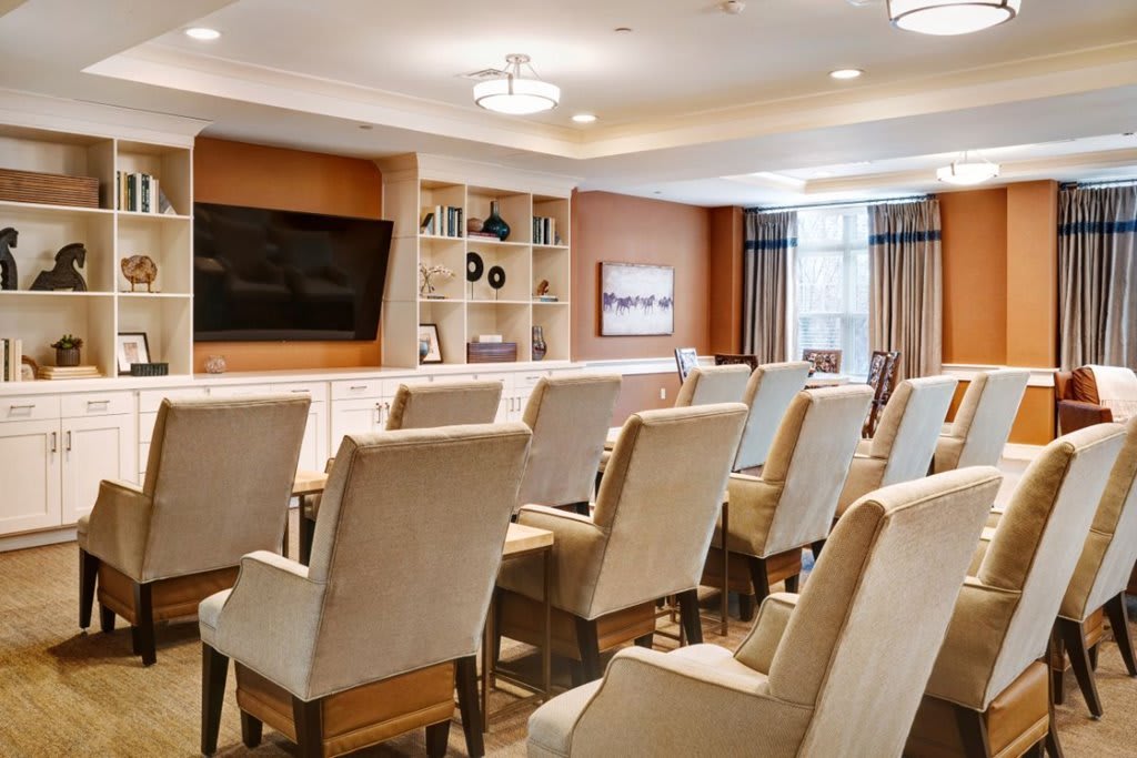 A well-furnished conference room equipped with comfortable chairs and a large television.