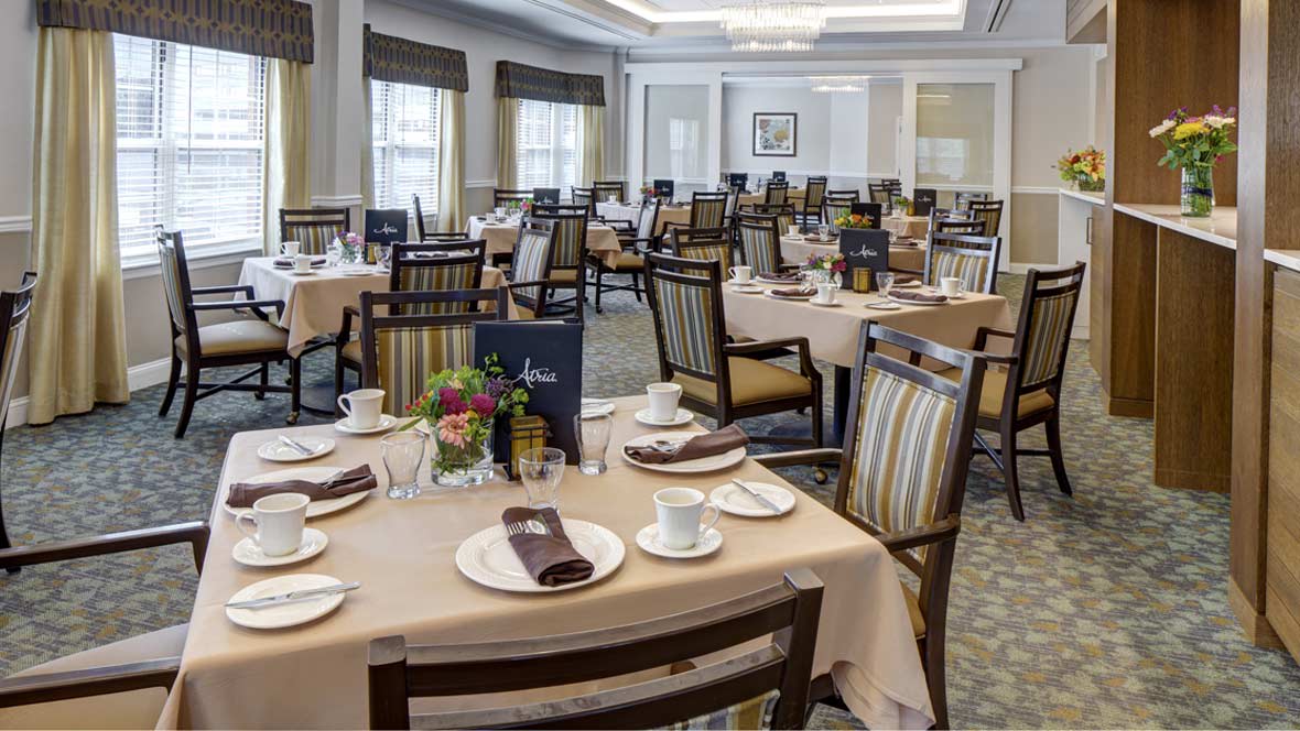 An elegantly set dining room with multiple tables and chairs, ready for guests.