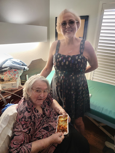 A heartfelt moment shared between two women, one caring for the other while enjoying a meal together.